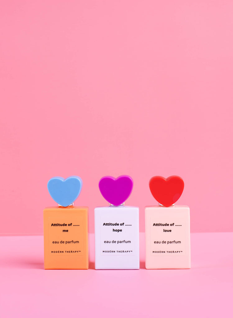 Three perfume bottles with heart-shaped stoppers on a pink background